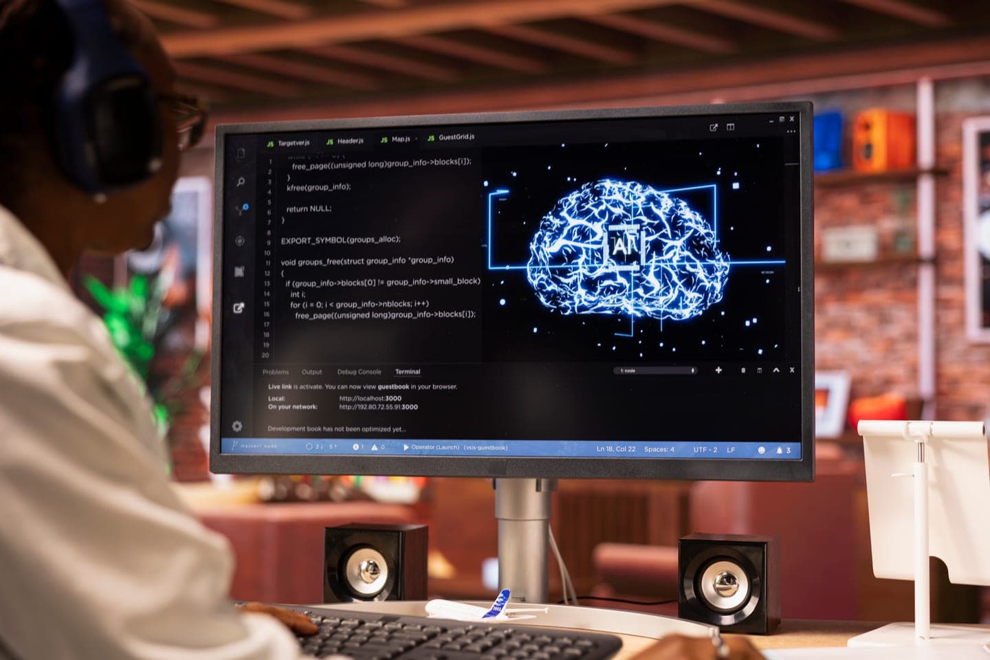 Over-the-shoulder view of a developer in headphones at a monitor showing a code editor and terminal beside a glowing blue AI brain graphic