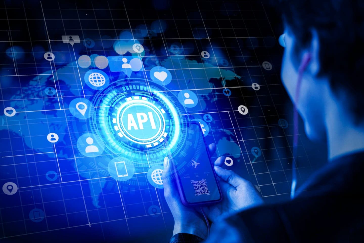 A person holds a smartphone in front of a glowing blue holographic API emblem surrounded by connected app and user icons on a dark grid