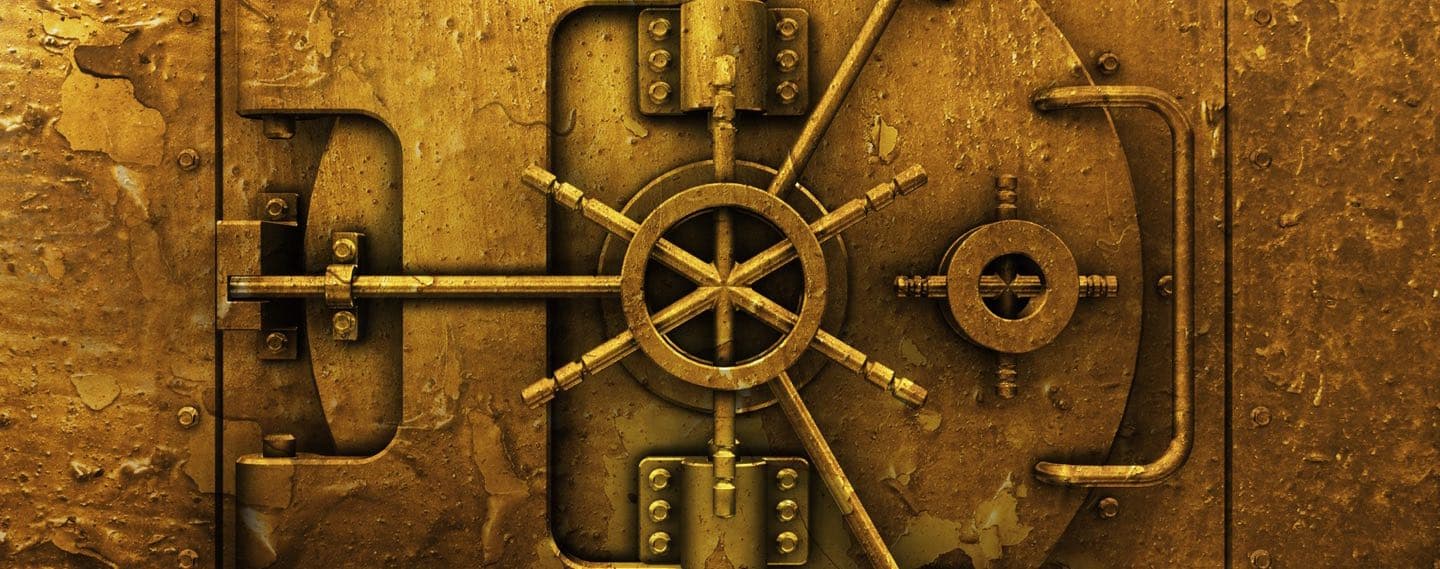 A heavy brass vault door with a spoked handle and exposed locking bolts, filling the frame.