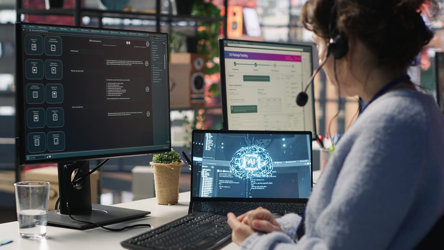Support agent in a headset at a desk with a laptop showing a glowing AI brain and monitors showing a chat assistant and a package tracking form